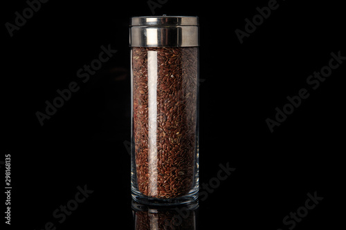 organic flax seeds in tall glass jar isolated on black