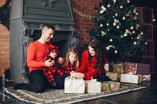 Beautiful mother in a red sweater. Family sitting near christmas gifts. Little girl and boy near christmas tree