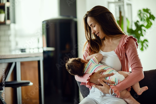 Bild auf Leinwand Young smiling mother breastfeeding her baby at home.