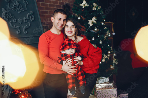 Beautiful mother in a red dress. Family standing on a room. Little girl and boy near christmas tree