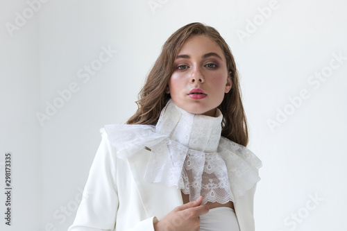 Young blonde girl in white suit and jabot on white background
