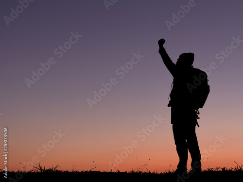 Silhouette of travel man with backpack raised hands on the mountain. success concept.