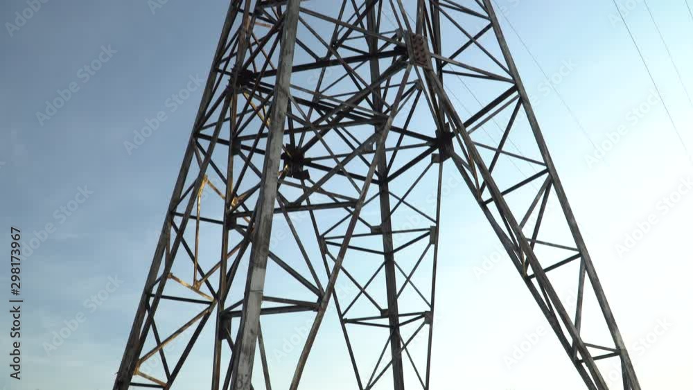Panoramic view from the bottom to the high voltage-current line metal construction on blue sky background. Panoramic view from the bottom to the high voltage-current line metal construction on blue sky background.