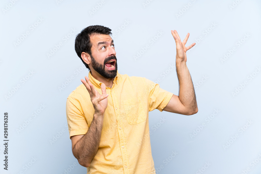 Fototapeta premium Young man with beard over isolated blue background nervous and scared