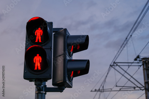 Fotografie Close up view of red traffic light at level crossing railway barrier, and blur outdoor background of arriving train at platform train station in small village countryside in Germany