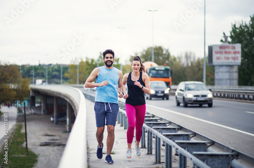 Running couple running together at bridge