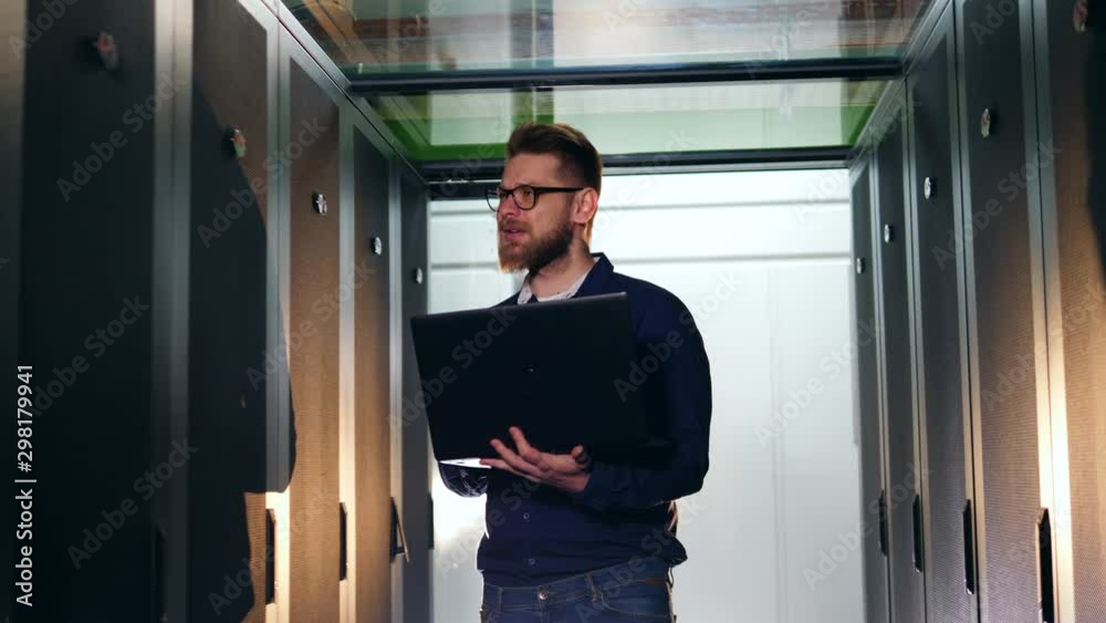 Computer engineer walks in data center, checking computers. Computer engineer walks in data center, checking computers.