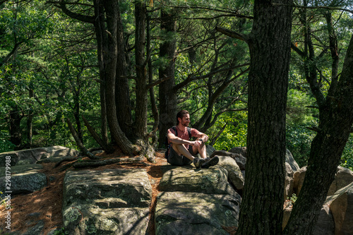 A young caucasian male hiker sitting the woods enjoying the outdoors.
