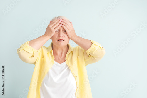Mature woman suffering from headache on light background
