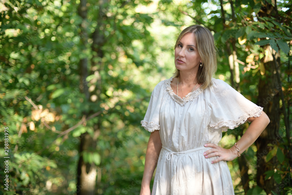 Woman standing in a forest and looking at the camera Woman standing in a forest and looking at the camera