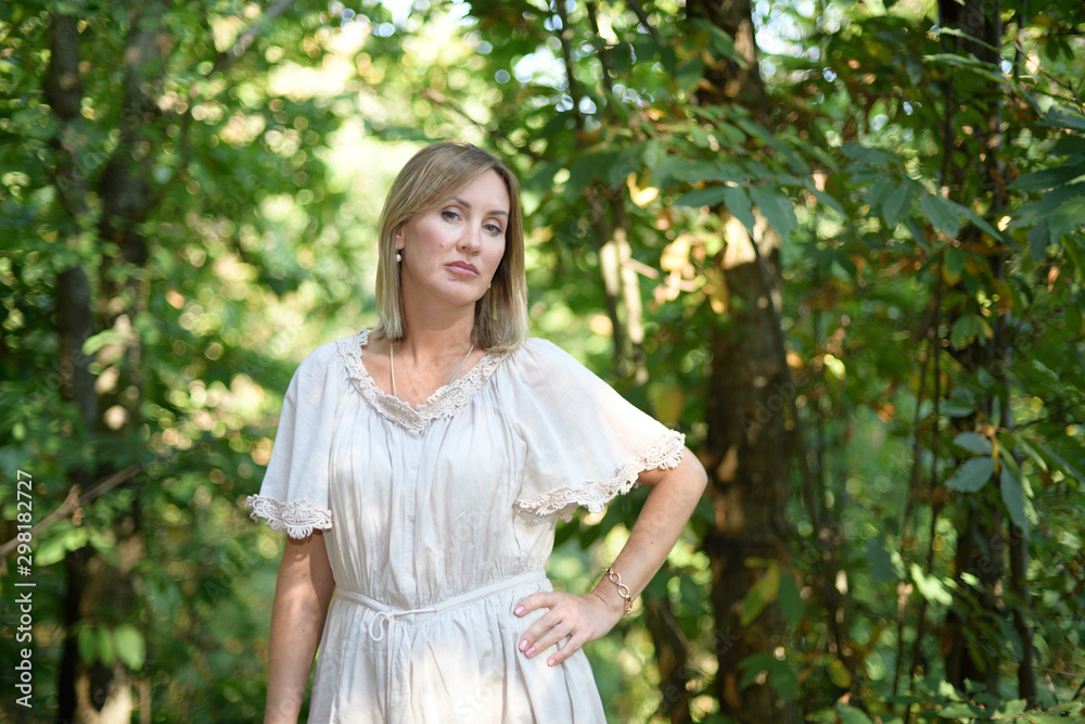 Woman standing in a forest and looking at the camera Woman standing in a forest and looking at the camera