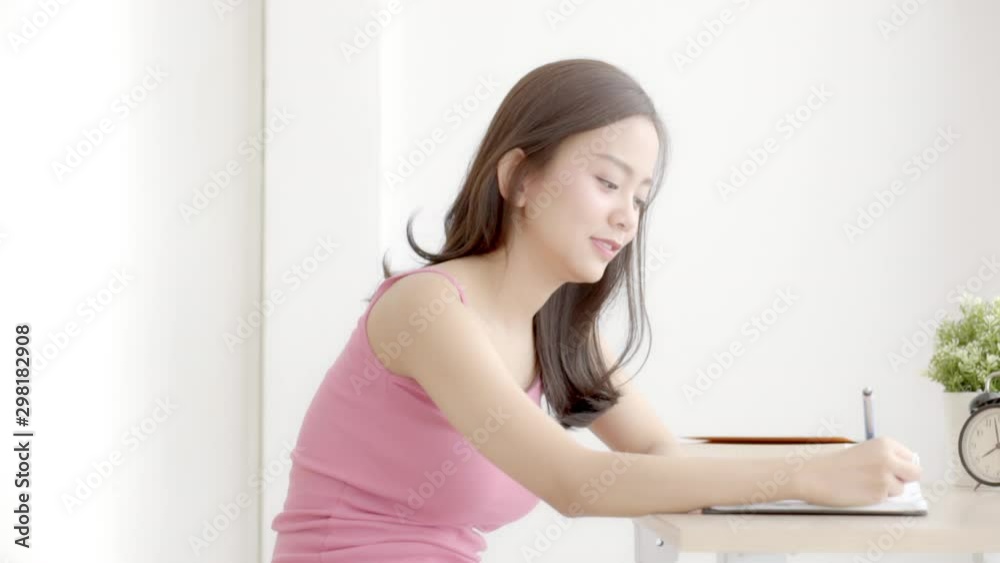 Beautiful young asian woman smiling sitting study and learning writing notebook and diary in the living room at home, girl homework, business woman working on table, education concept. Beautiful young asian woman smiling sitting study and learning writing notebook and diary in the living room at home, girl homework, business woman working on table, education concept.