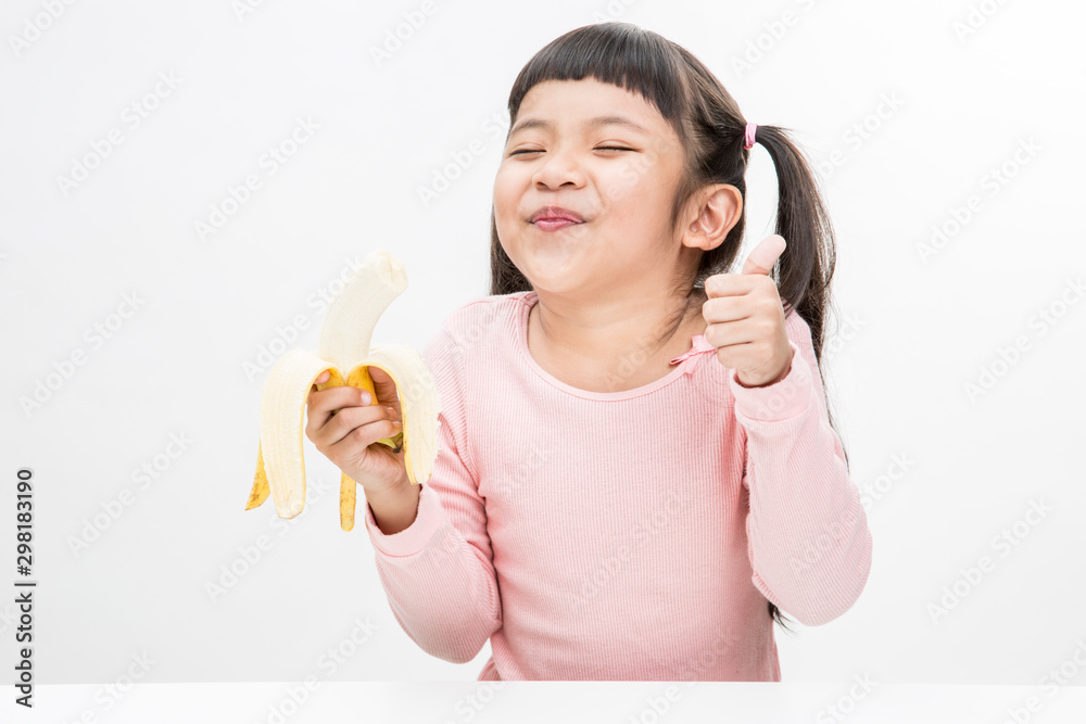 Cute little asian girl in casual clothes eating banana looks very happy,isolated on white background.