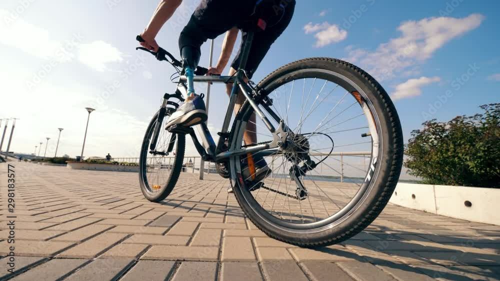 A man with a bionic leg is riding a bicycle outdoors A man with a bionic leg is riding a bicycle outdoors