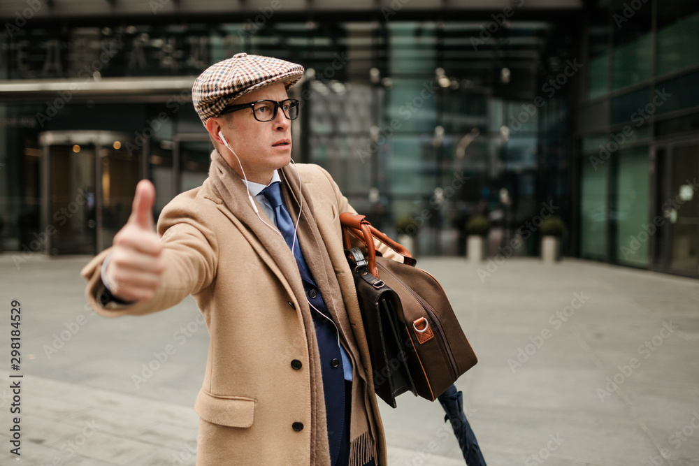 Manager a man loaded with bags and Luggage stands on the street in the business district and tries to catch a taxi to the airport Manager a man loaded with bags and Luggage stands on the street in the business district and tries to catch a taxi to the airport