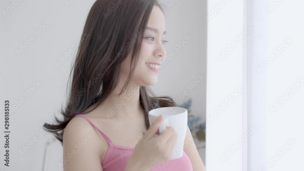 Beautiful portrait young asian woman smile and drink a cup of coffee with relax in the morning at window, girl happy with leisure breakfast is beverage for fresh, lifestyle concept, slow motion. Beautiful portrait young asian woman smile and drink a cup of coffee with relax in the morning at window, girl happy with leisure breakfast is beverage for fresh, lifestyle concept, slow motion.