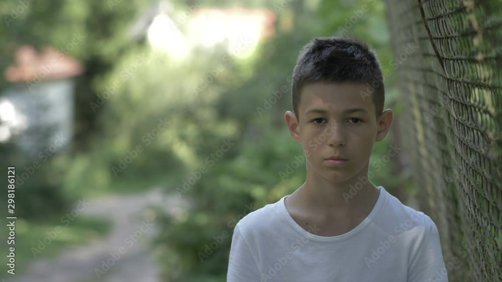portrait of a serious caucasian boy outdoors close-up