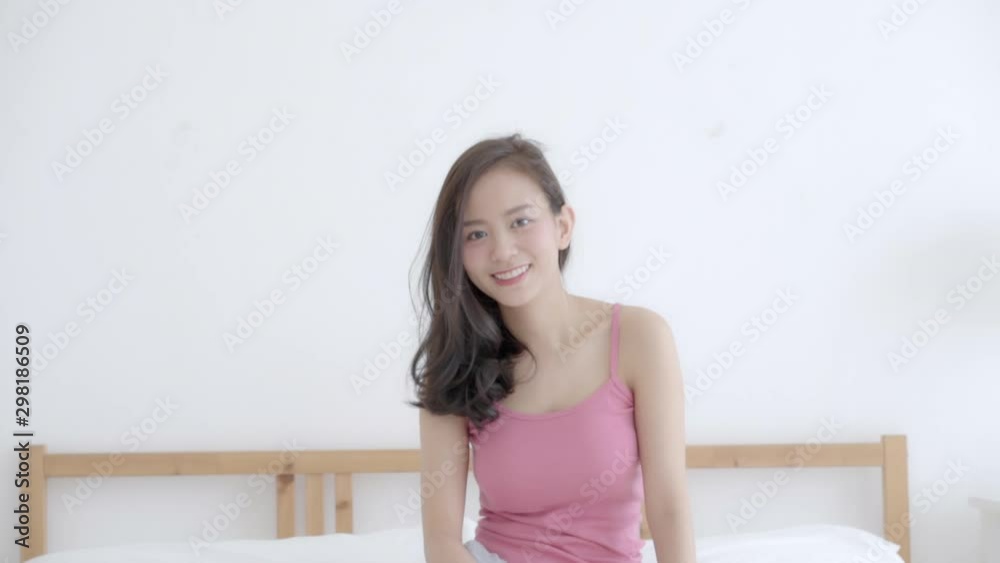 Beautiful closeup portrait young asian woman with smiling and laughing sitting on bed in bedroom, girl looking at camera with happy and funny, slow motion. Beautiful closeup portrait young asian woman with smiling and laughing sitting on bed in bedroom, girl looking at camera with happy and funny, slow motion.