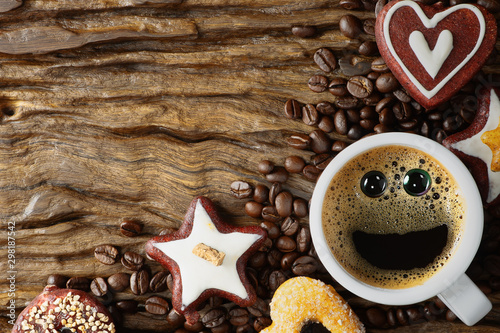 food and beverage background of a cup of black coffee with smling face and assortment of cookies and roasted arabica coffee beans on wooden plank © Mongkolchon