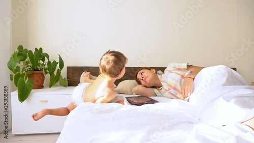 Mom and son watch tablet in bedroom