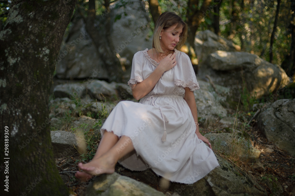 Woman in a forest sitting and relaxing as the sun goes down Woman in a forest sitting and relaxing as the sun goes down