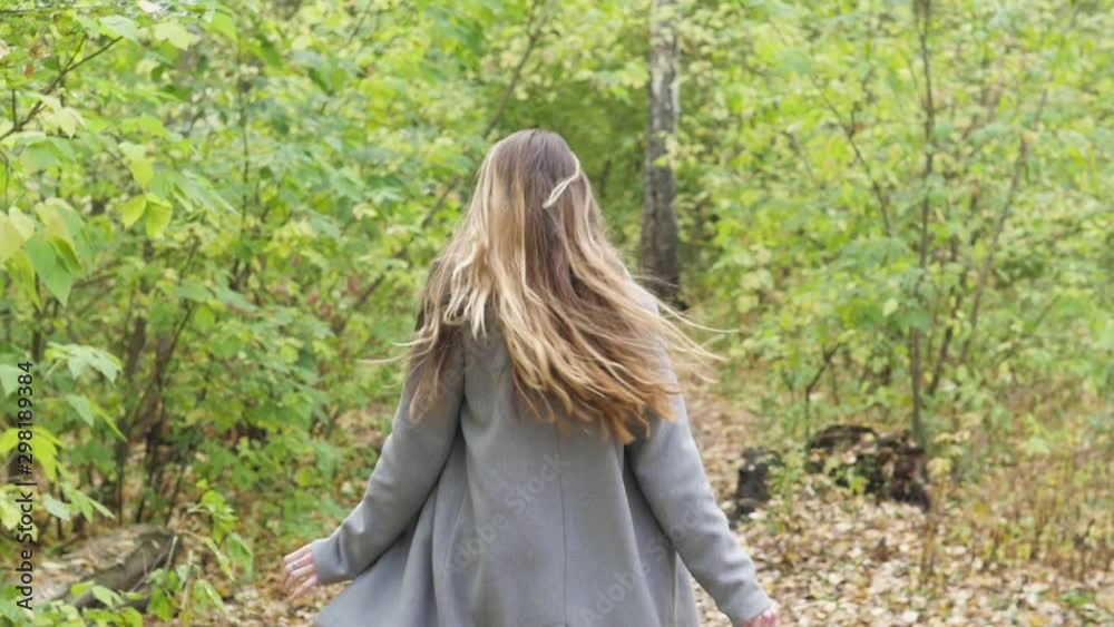 Young cheerful woman enjoying an autumn day in a park. A woman walks in the park whirling. Young cheerful woman enjoying an autumn day in a park. A woman walks in the park whirling.