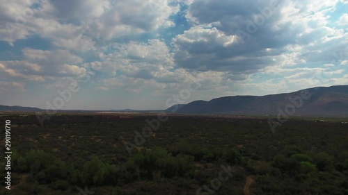 Time-lapse of clouds moving over mountains & bush field. Shadows of clouds moving & revealing the sun and the beautiful nature underneath it. photo