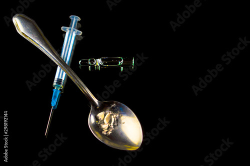Drugs. Syringe, spoon with heroin and ampoule on a black background. 