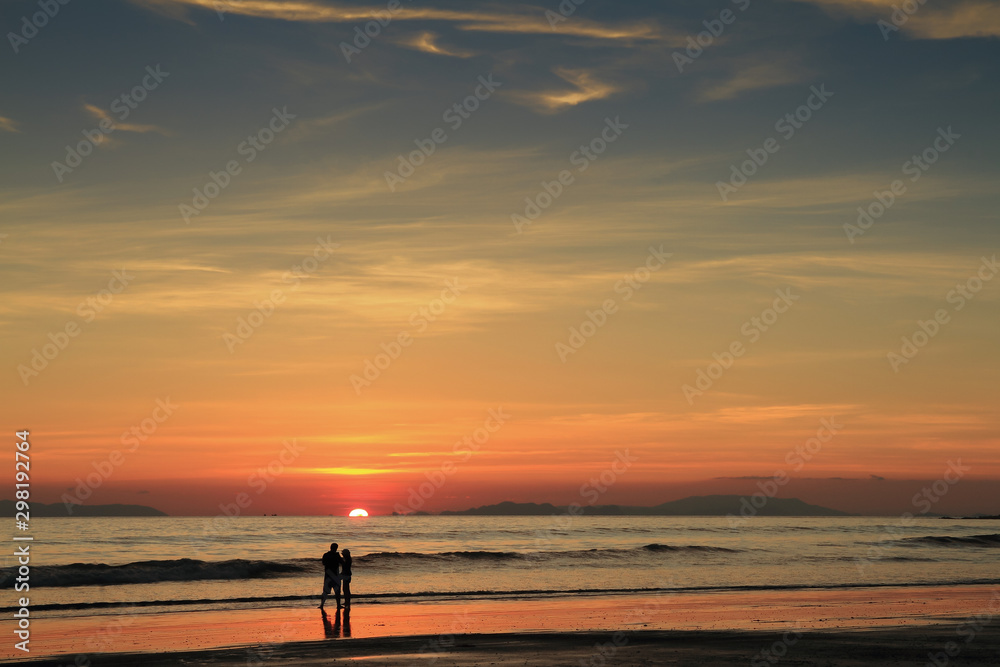 Fototapeta premium The perfect sunset ,a silhouetted couple take in the last vestiges of the day on a the beach,koh Phayam,ranong thailand