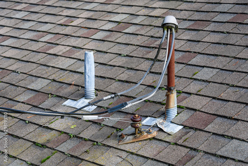 Suburban house rooftop, asphalt shingles, electrical power masthead, skylight with cover, roof vents