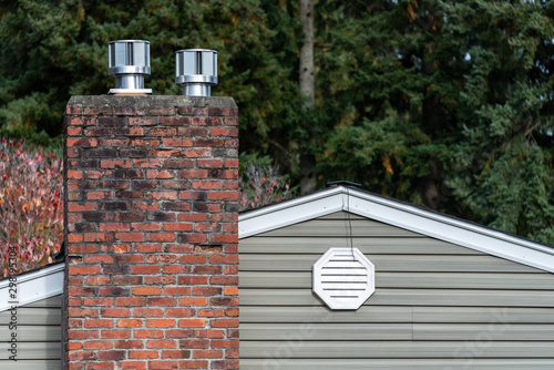 Obraz na plátne Exterior wall of suburban house, old brick chimney with chimney vents, attic fan