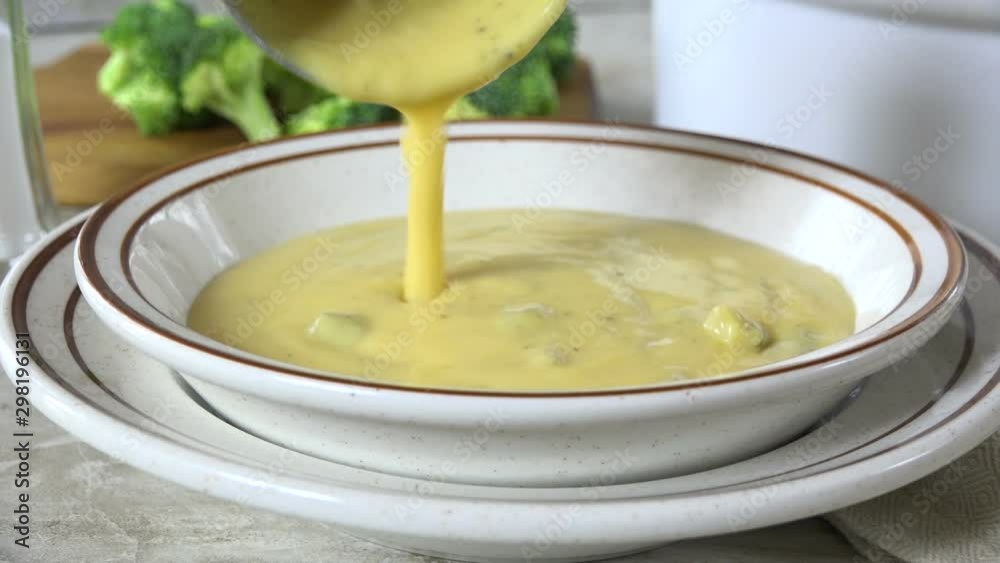 Ladling broccoli cheese soup into a bowl slow motion Ladling broccoli cheese soup into a bowl slow motion