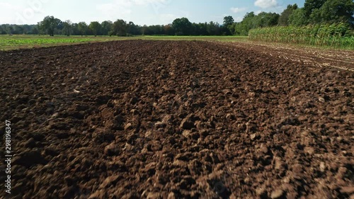 Ploughed field in autumn, flyover, hedges and trees in background, agiculture and cultivating soil concept