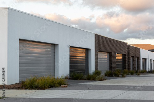 Modern car garages reflecting golden afternoon light in suburban area.