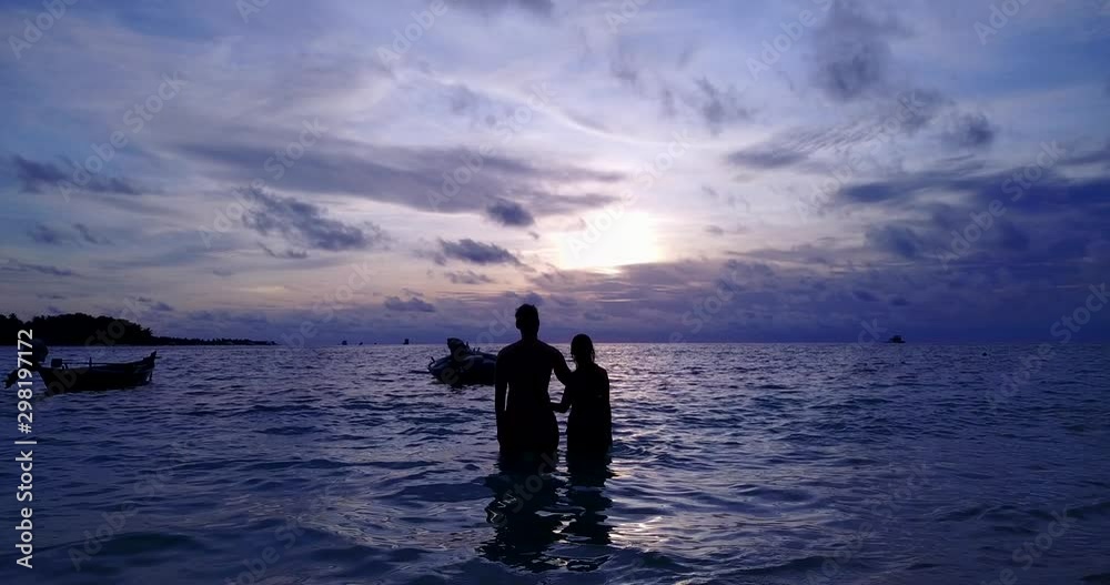 lovely couple hugging in the Caribbean standing in shallow water at sunset lovely couple hugging in the Caribbean standing in shallow water at sunset