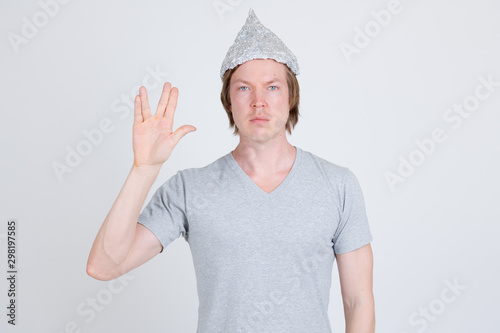 Photography Young man wearing tin foil hat as conspiracy theory concept showing Vulcan salut