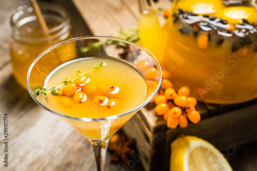 Hot autumn cocktail with sea buckthorn and orange juice in martini glass on the rustic background. Selective focus. Shallow depth of field. photo