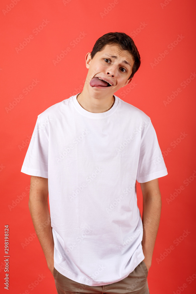 Handsome funny man shows tongue on red background