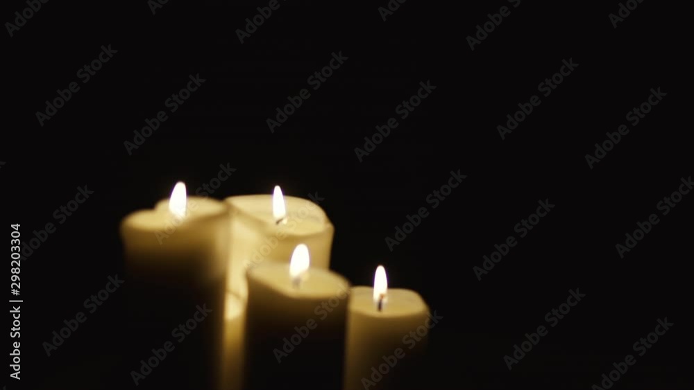 Shift from left to right: four candles on a table on a black background Shift from left to right: four candles on a table on a black background
