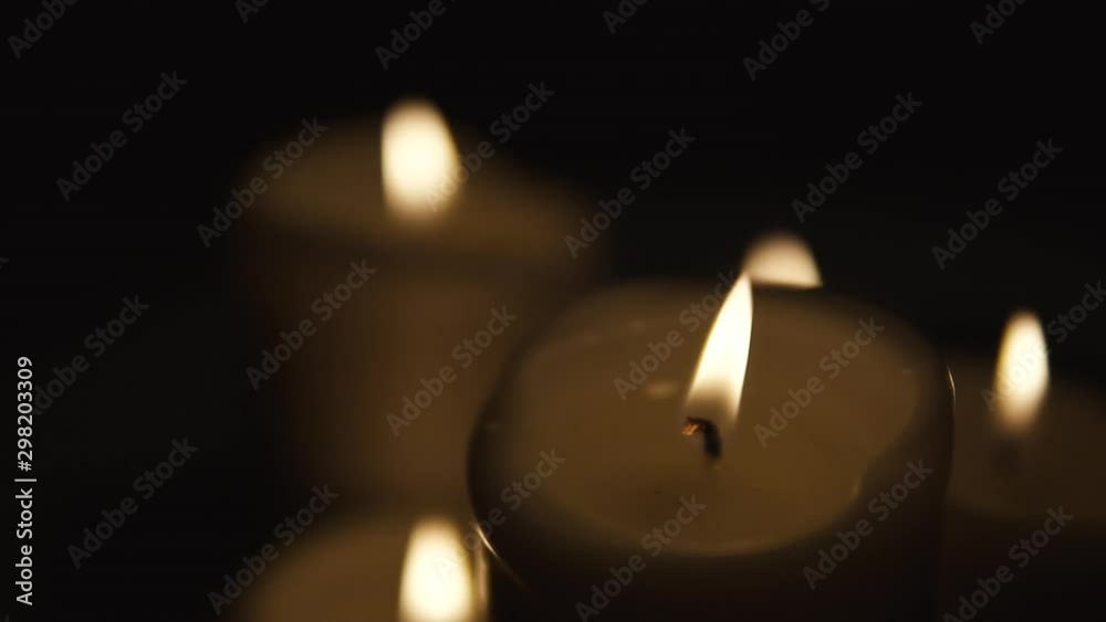 Slow movement over burning candles, composition on black background, candles of different sizes stand side by side, slow motion Slow movement over burning candles, composition on black background, candles of different sizes stand side by side, slow motion