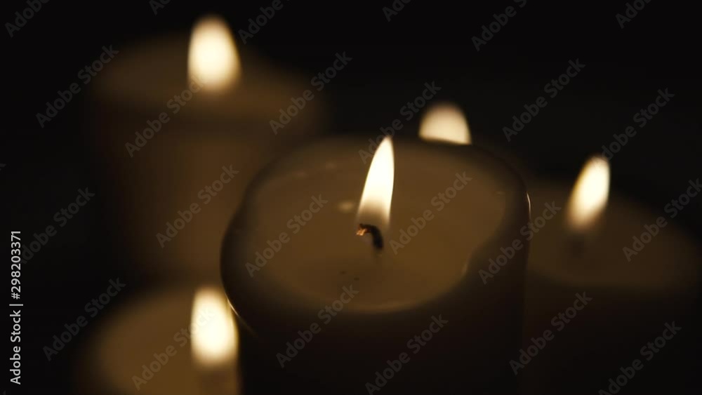 Slow movement over burning candles, composition on black background, candles of different sizes stand side by side, slow motion Slow movement over burning candles, composition on black background, candles of different sizes stand side by side, slow motion