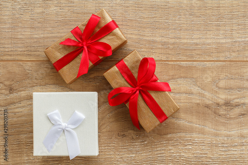 Gift boxes with red ribbons on wooden boards.