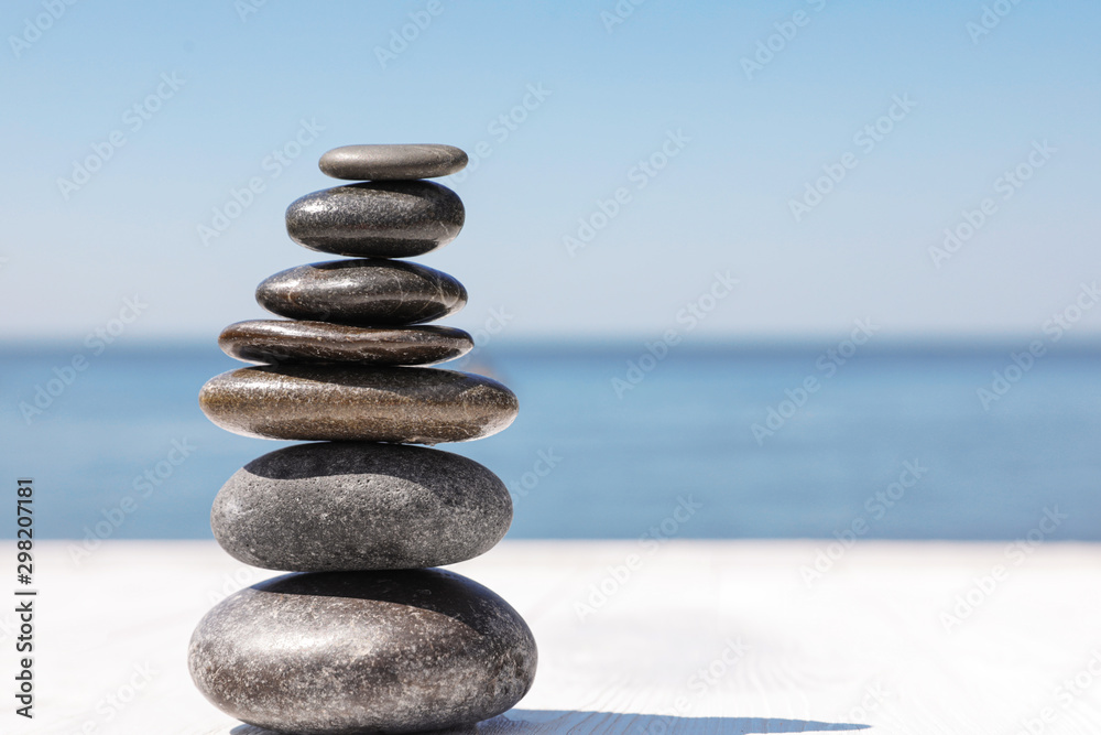 Stack of stones on wooden pier near sea, space for text. Zen concept