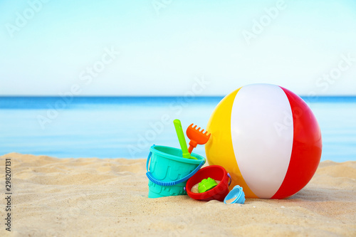 Set of plastic beach toys and colorful ball on sand near sea. Space for text photo