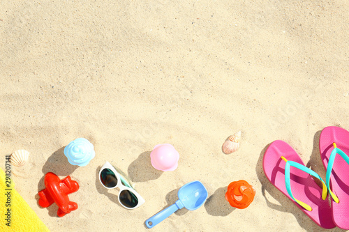Flat lay composition with plastic beach toys on sand. Space for text
