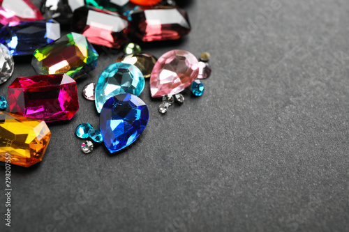 Different beautiful gemstones on black background. Space for text