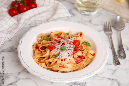 Tasty pasta with tomatoes, cheese and basil on white marble table