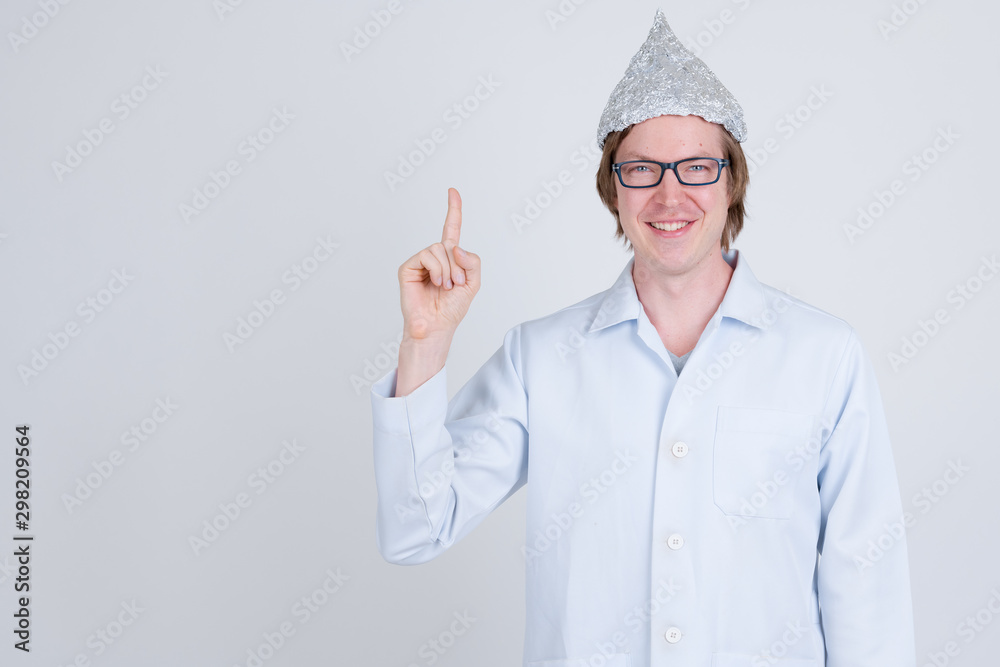 Happy young man doctor with tinfoil hat pointing up