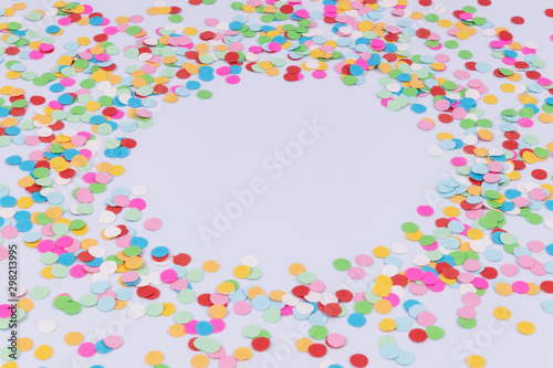 Side view of a round ornament made of scattered confetti on white background