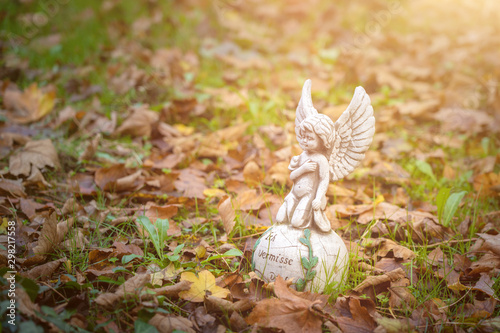 Little angel on a white ball with the german inscription for i miss you, a lot of autumn leaves